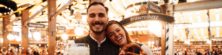Besucher im Festzelt mit Breze und Maß Oktoberfestbier